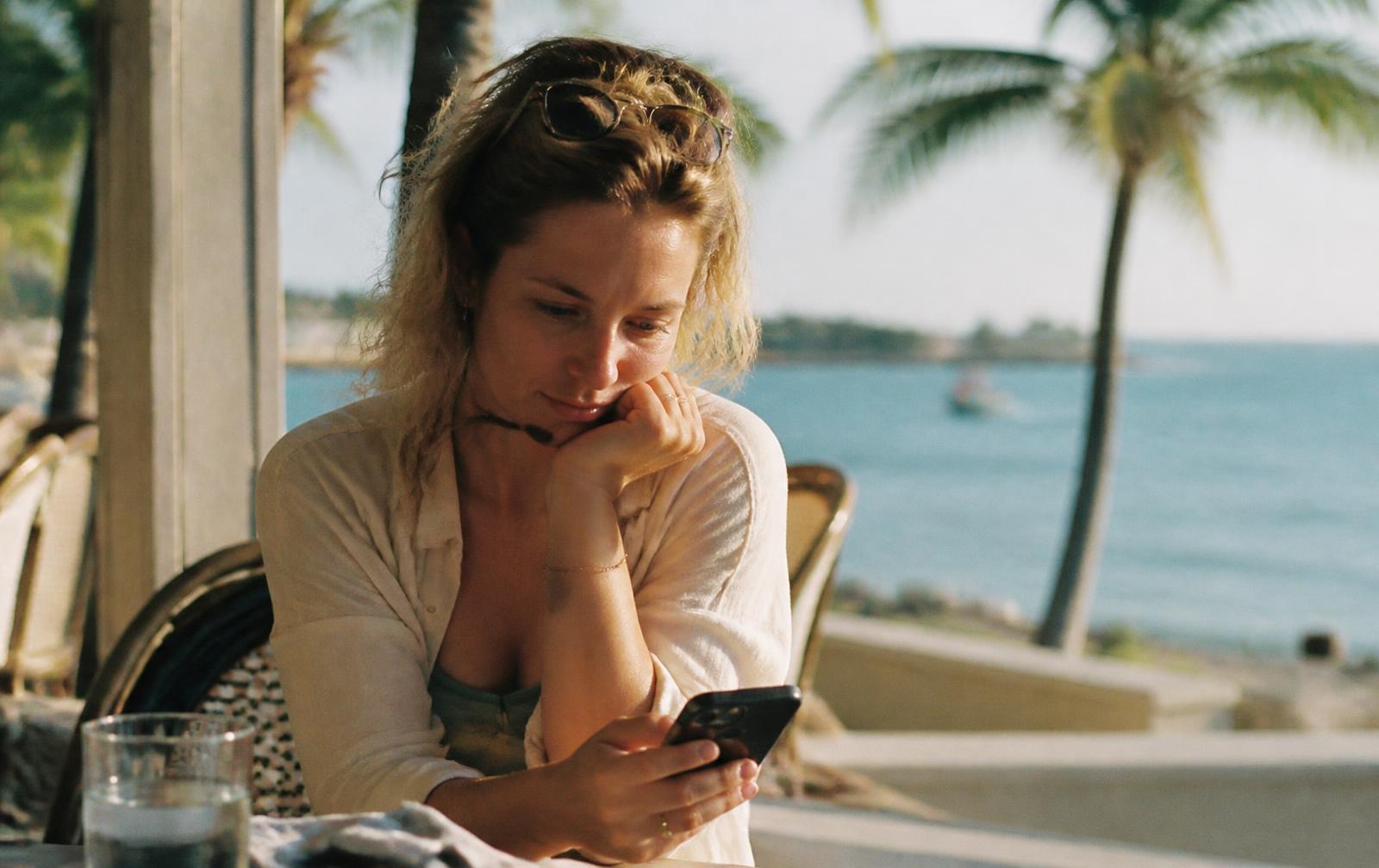 A traveller at a Southwest Florida waterfront cafe reading her phone while deciding where to go