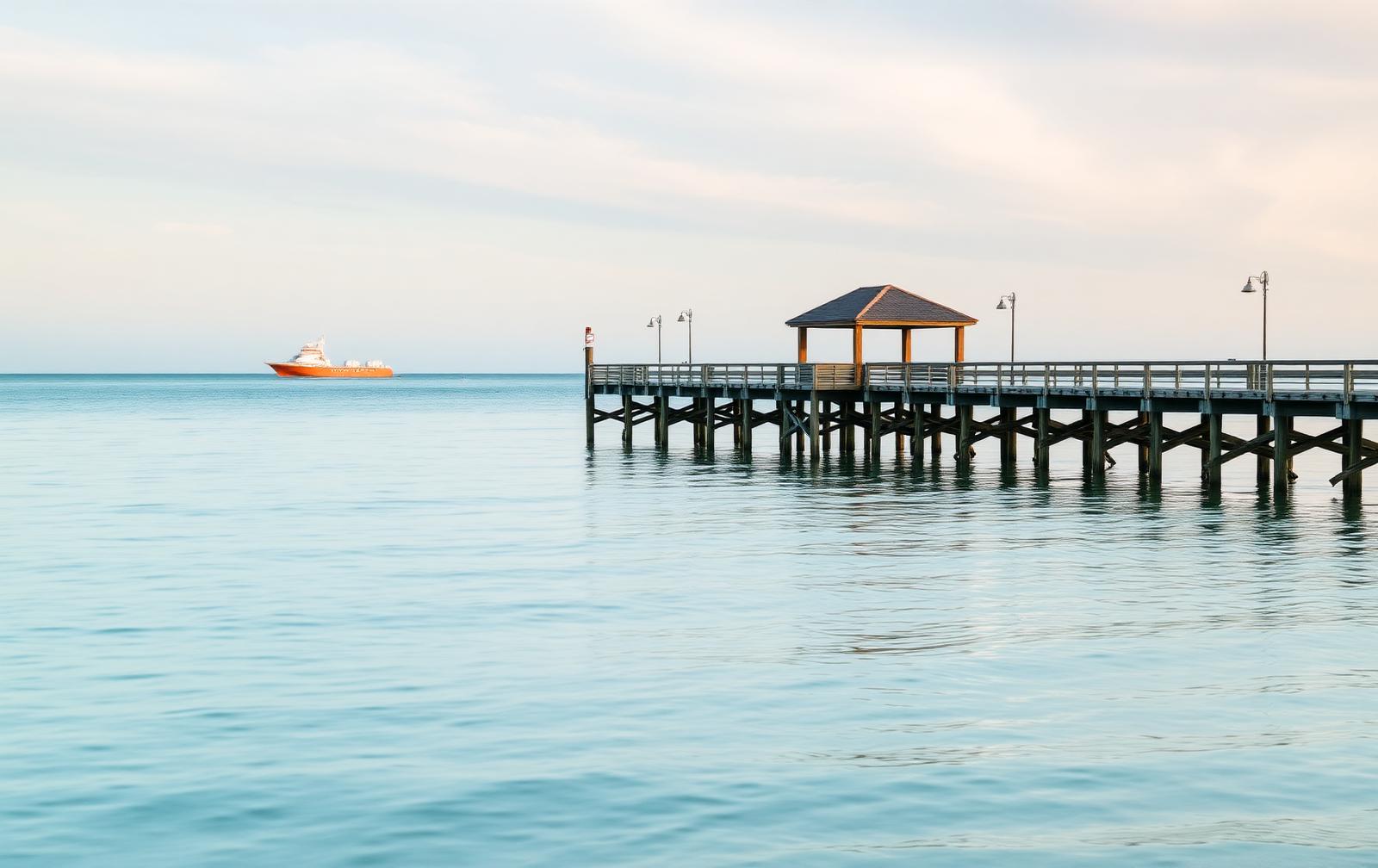 A quiet Southwest Florida pier at first light with calm gulf water and an open horizon